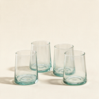 Set of four tumblers in recycled glass on a cream background