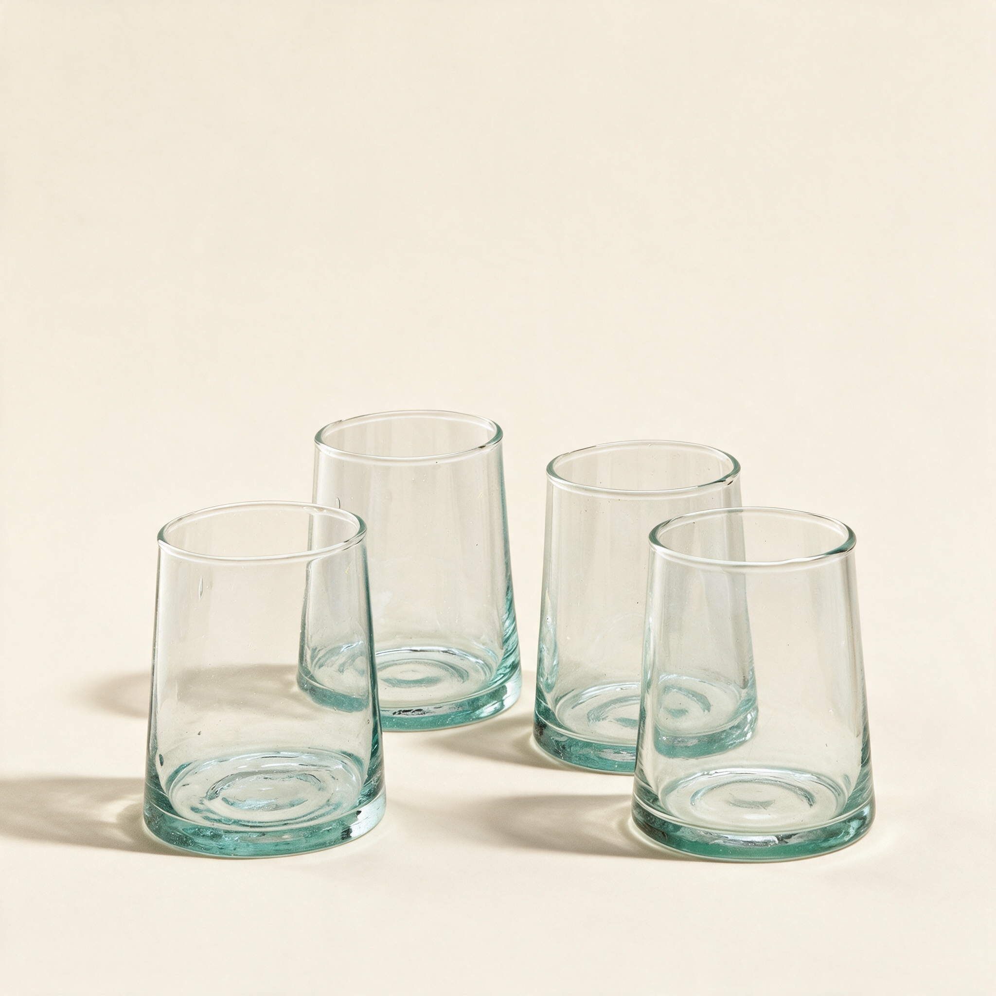 Set of four tumblers in recycled glass on a cream background