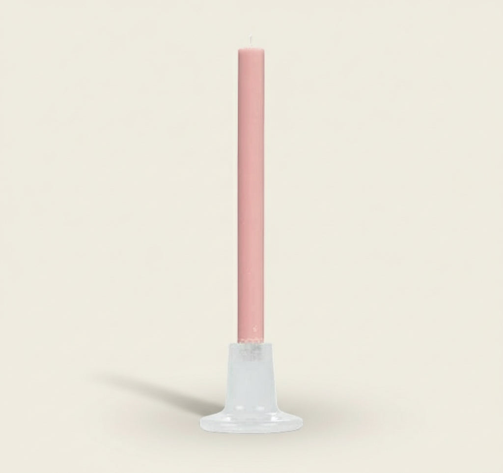 Pink candle on a white stand against a white background