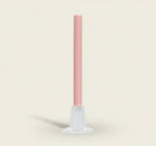 Pink candle on a white stand against a white background