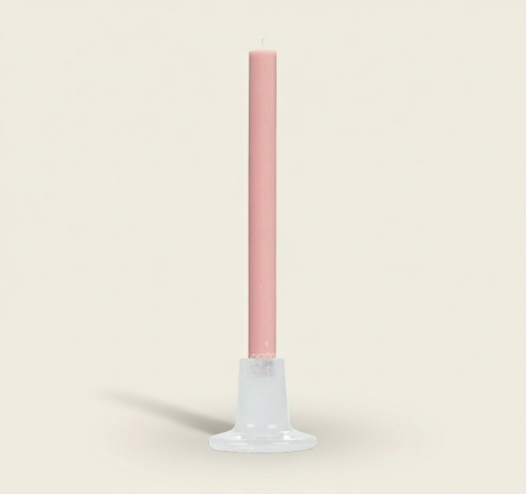 Pink candle on a white stand against a white background